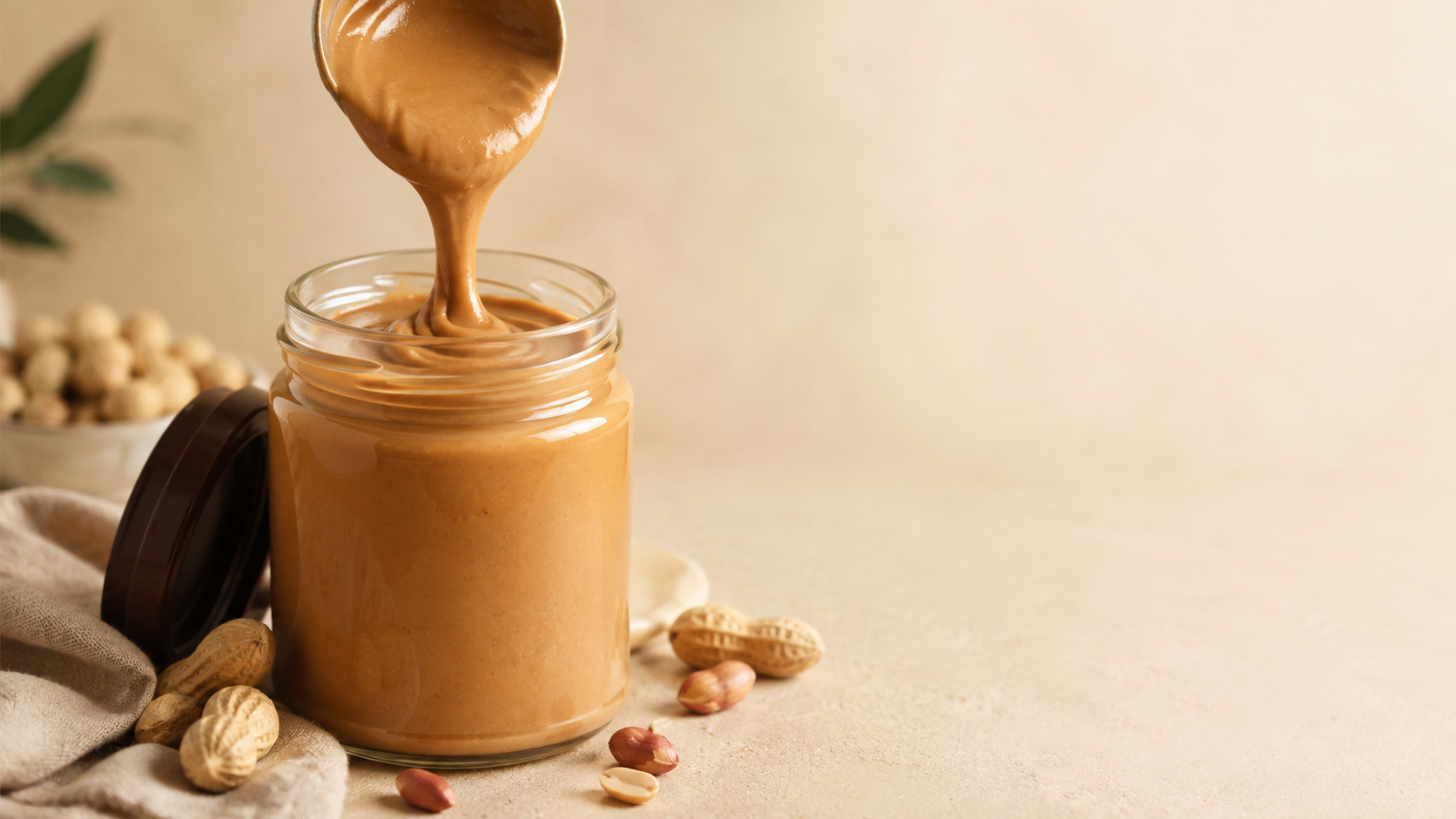 Crema de cacahuate natural llenando un frasco de vidrio sin etiqueta.